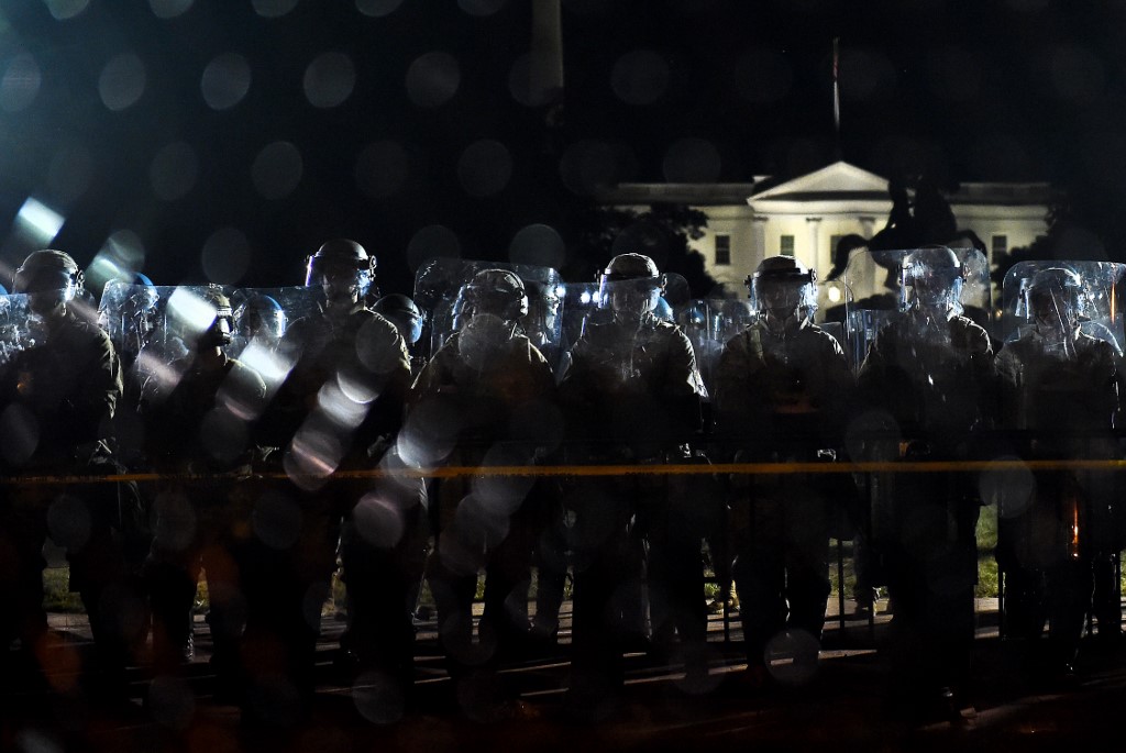 Police officers hold a perimeter behind the metal fence recently erected in front of the White House demonstrators gather to protest the killing of George Floyd on June 2, 2020 in Washington, DC. - Anti-racism protests have put several US cities under curfew to suppress rioting, following the death of George Floyd in police custody. (Photo by Olivier DOULIERY / AFP)